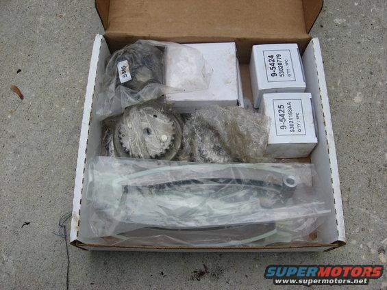 Box of engine timing components, including gears and a chain, with part numbers visible on boxes