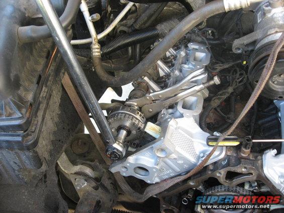 Engine repair in progress, vise grips holding a timing chain component