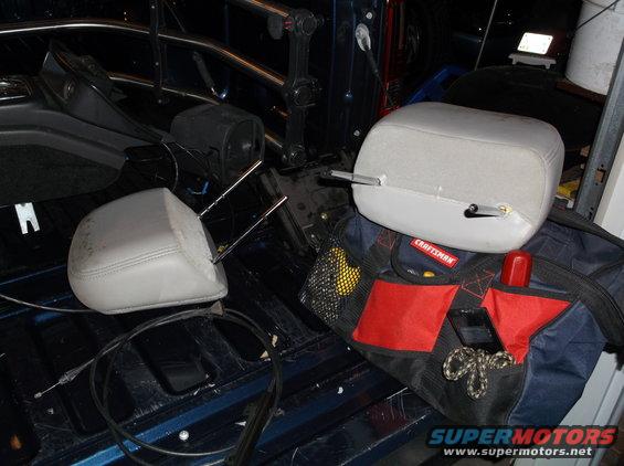 Two car headrests and a Craftsman tool bag are in the bed of a dark blue pickup truck