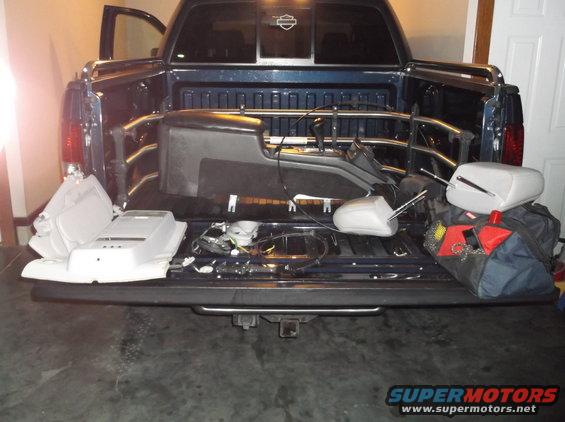 Pickup truck bed loaded with car interior parts and bags