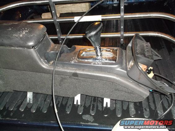 Center console with gear shifter from a 2003 Mercury Grand Marquis, showing wear and tear, inside a truck bed