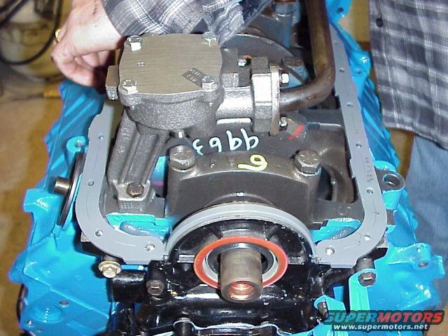 Installing oil pan gasket on engine block. Someone is holding the oil pump