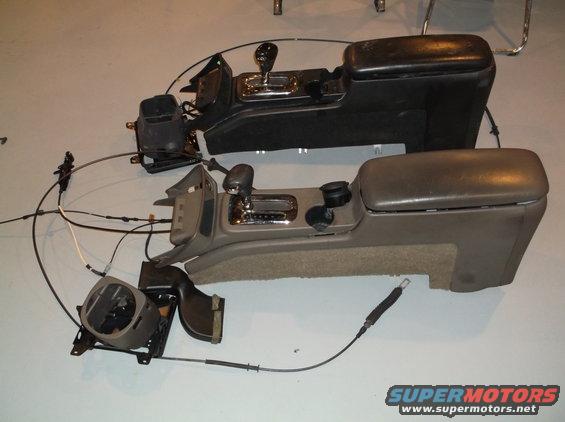 Two car center consoles with gear shifters and armrests, one black and one tan