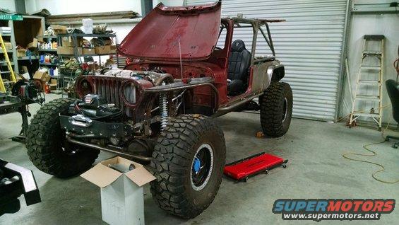 Modified Jeep CJ in a garage with hood open and roll cage installed