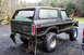 1979 Ford Bronco - Rear view of a lifted black 1979 Ford Bronco, modified with large off-road tires and mud flaps.