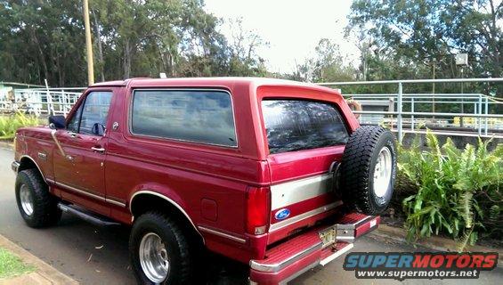 Red 1991 Ford Bronco parked outdoors, rear quarter view showing spare tire on the back