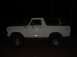 1979 Ford Bronco - A white Ford Bronco is parked outdoors at night, its side profile illuminated against the dark background.