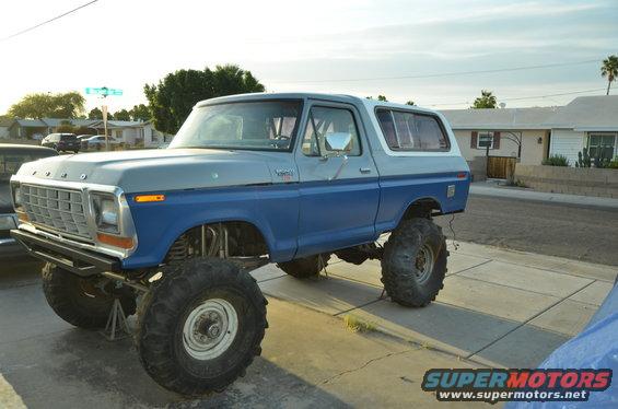 Lifted 1978 Ford Bronco, blue and gray two-tone paint, large off-road tires, parked on a driveway