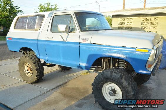 Two-tone blue and white lifted Ford Bronco with large off-road tires