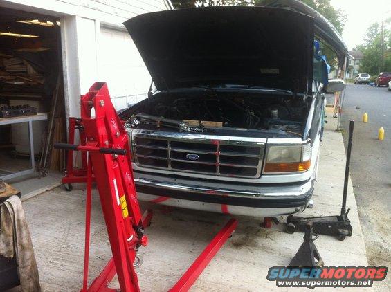 1992 Ford Bronco front end with hood open, engine visible, parked in driveway with engine hoist nearby