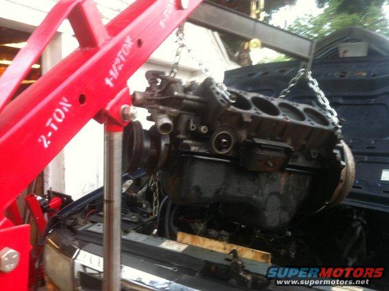 engine being lifted out of a vehicle with a red engine hoist