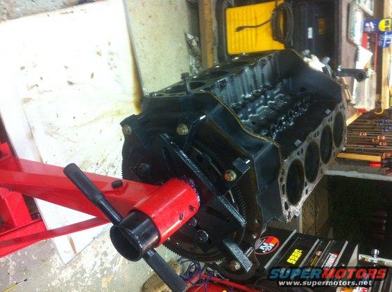 Black engine block on a red engine stand, viewed from the side with cylinders visible