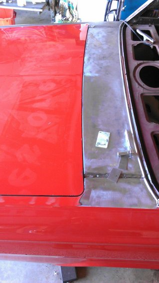 Red car door and unpainted fender section with visible repair work and a small sticker