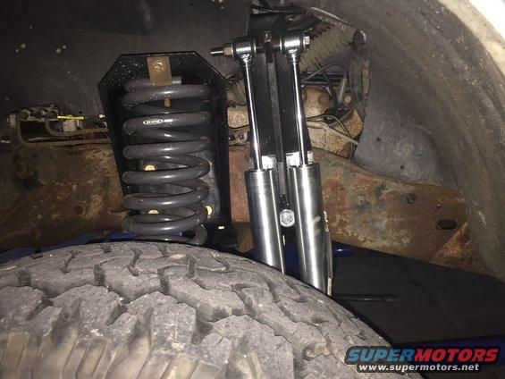 Close-up of a vehicle's suspension with a coil spring and dual shock absorbers