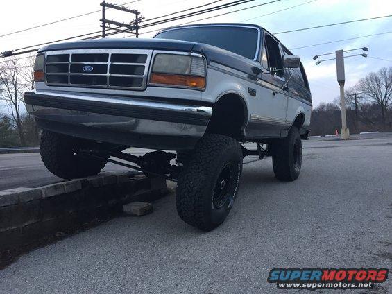 1994 Ford Bronco parked with front driver's side tire on a low wall