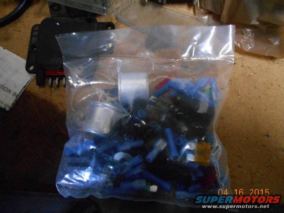 Bag of blue and red electrical connectors with a black electronic component on a wooden surface