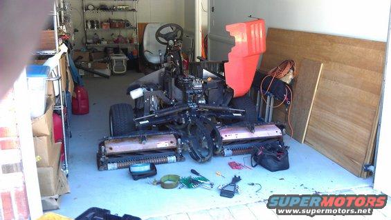 Disassembled lawn mower with tools on the floor