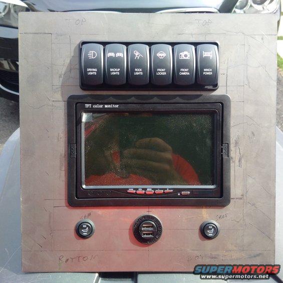 Metal panel with six toggle switches labeled driving lights, backup lights, rock lights, front locker, front camera, and winch power. Below is a TFT color monitor and two USB ports