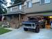 1978 Ford Bronco - 1978 Ford Bronco in front of a house, showing its front grille and interior with a driver.