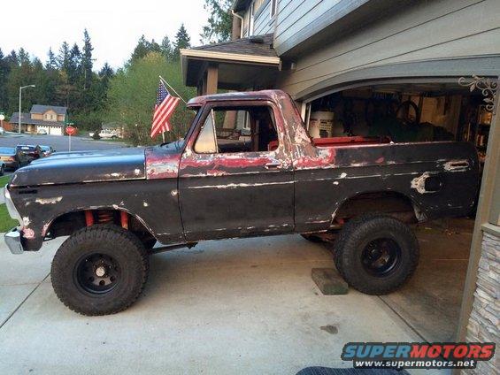 Side view of a black and red 1978 Ford Bronco with lifted suspension
