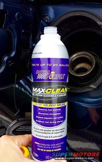 Royal Purple Max-Clean fuel additive bottle held near a gas tank opening