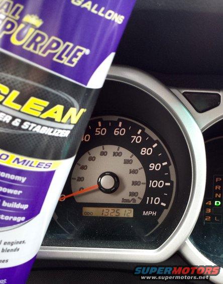 Dashboard gauges and a bottle of purple cleaner. Odometer reads 132512