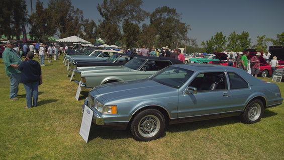 Light blue coupe with a vinyl roof parked on grass at a car show