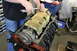 1979 Ford Bronco - Mechanic installs a yellow perforated cover onto an engine block during an engine build.