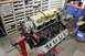 1979 Ford Bronco - Engine block assembly on a stand in a workshop with parts bins in the background.