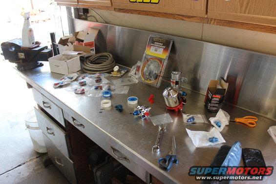 Workbench with fuel lines, fittings, a Holley fuel pump, and tools