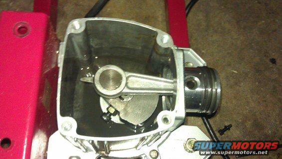 Air compressor cylinder with piston and connecting rod, some oil visible inside
