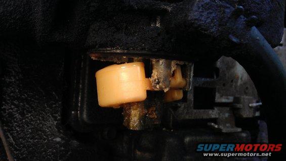 Carburetor float bowl with beige float and yellow needle valve