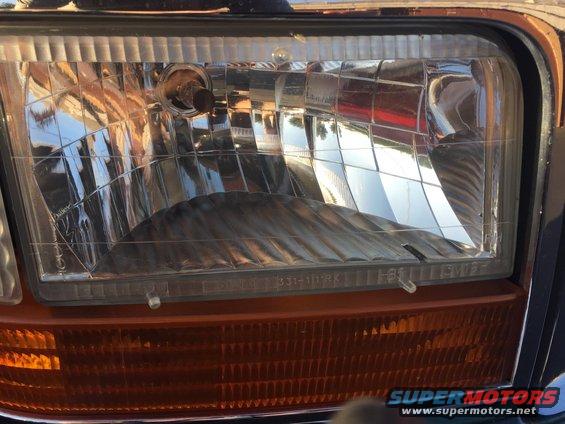 Headlight and amber turn signal assembly on a 1992 Ford Bronco, showing a clear lens with internal fluting and a textured amber lower section