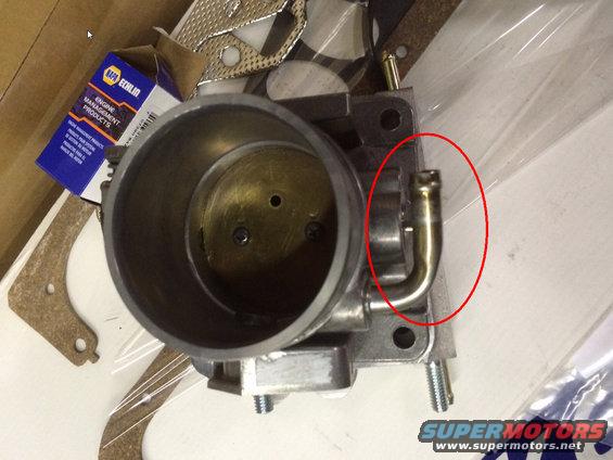 Throttle body with a brass vacuum hose fitting circled in red. NAPA Echlin box in background