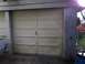1988 Ford Bronco - A beige sectional garage door is shown with a partial view of a white vehicle to the left.