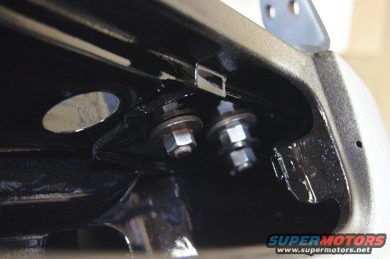 Close-up of two bolts and nuts securing a metal bracket to a vehicle frame