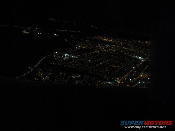 City lights spread across a dark landscape, seen from above at night