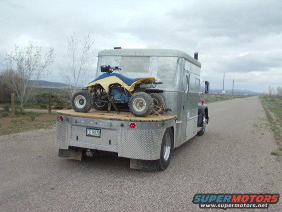 Aluminum truck with ATV on flatbed, rear view. License plate CH-18629