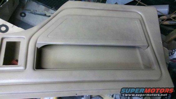 Tan interior door panel with a rectangular cutout and a large storage pocket
