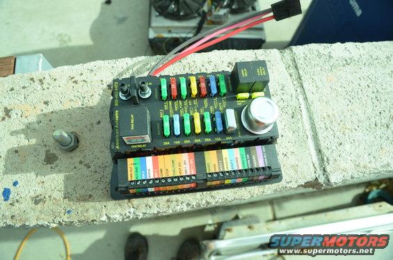 Automotive fuse box with various colored fuses and relays, labeled for different circuits