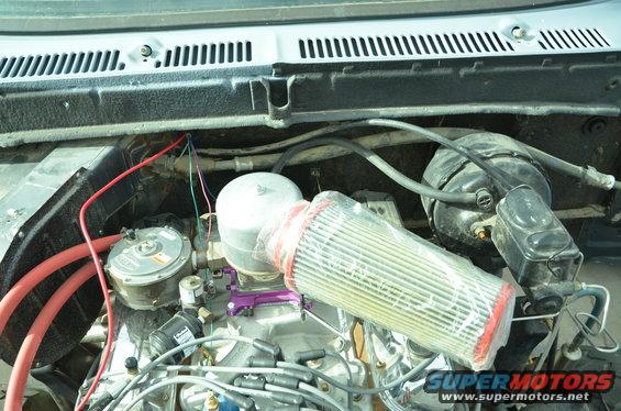 Engine bay showing carburetor, aftermarket air filter, brake booster, and wiring