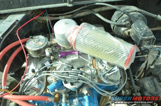 Engine bay with air filter, carburetor, brake booster, and various hoses and wires