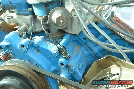 Blue painted engine block with a belt and pulley, wires, and a distributor cap
