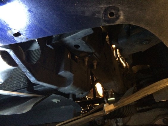 Underside view of car's front suspension and radiator area. Blue body panel visible above