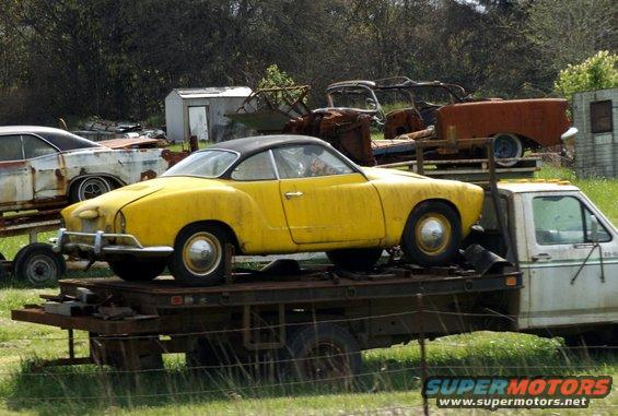 Yellow Volkswagen Karmann Ghia coupe on a flatbed truck, side view