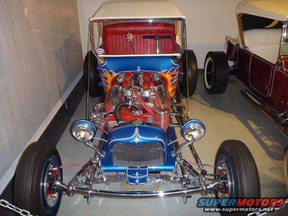 Blue hot rod with exposed engine, flames, and red interior
