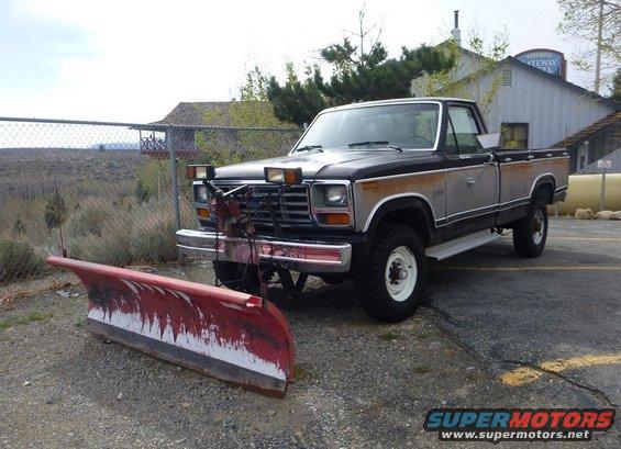 1980s pickup truck with snow plow attached to front bumper, parked outdoors