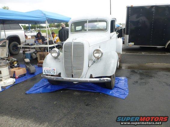 White pickup truck with a chrome grille and bumper, parked on a blue tarp