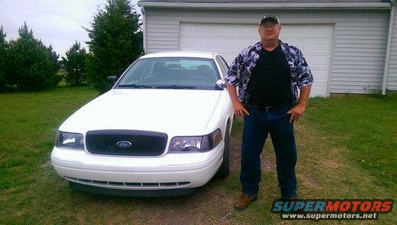 White 2000 Mercury Grand Marquis with a man standing beside it in front of a garage