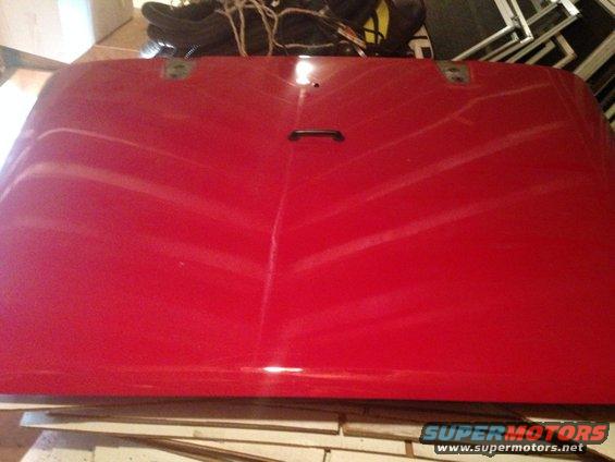 Red vehicle hood with a black handle and two mounting points